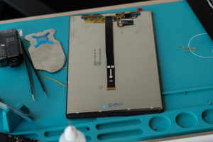 Écran de tablette avec sa nappe sur un tapis de réparation, remplacement d'écran à l'atelier de Chamalières