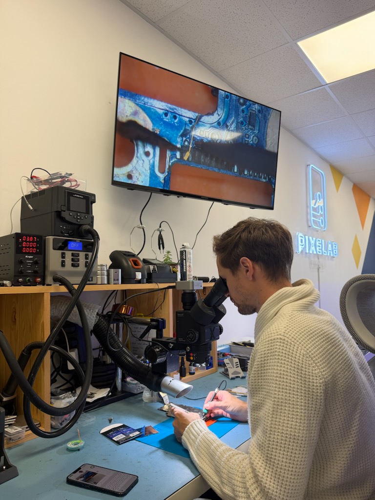 Microsoudure : technicien de Pixelab Industry réparant une carte électronique sous microscope