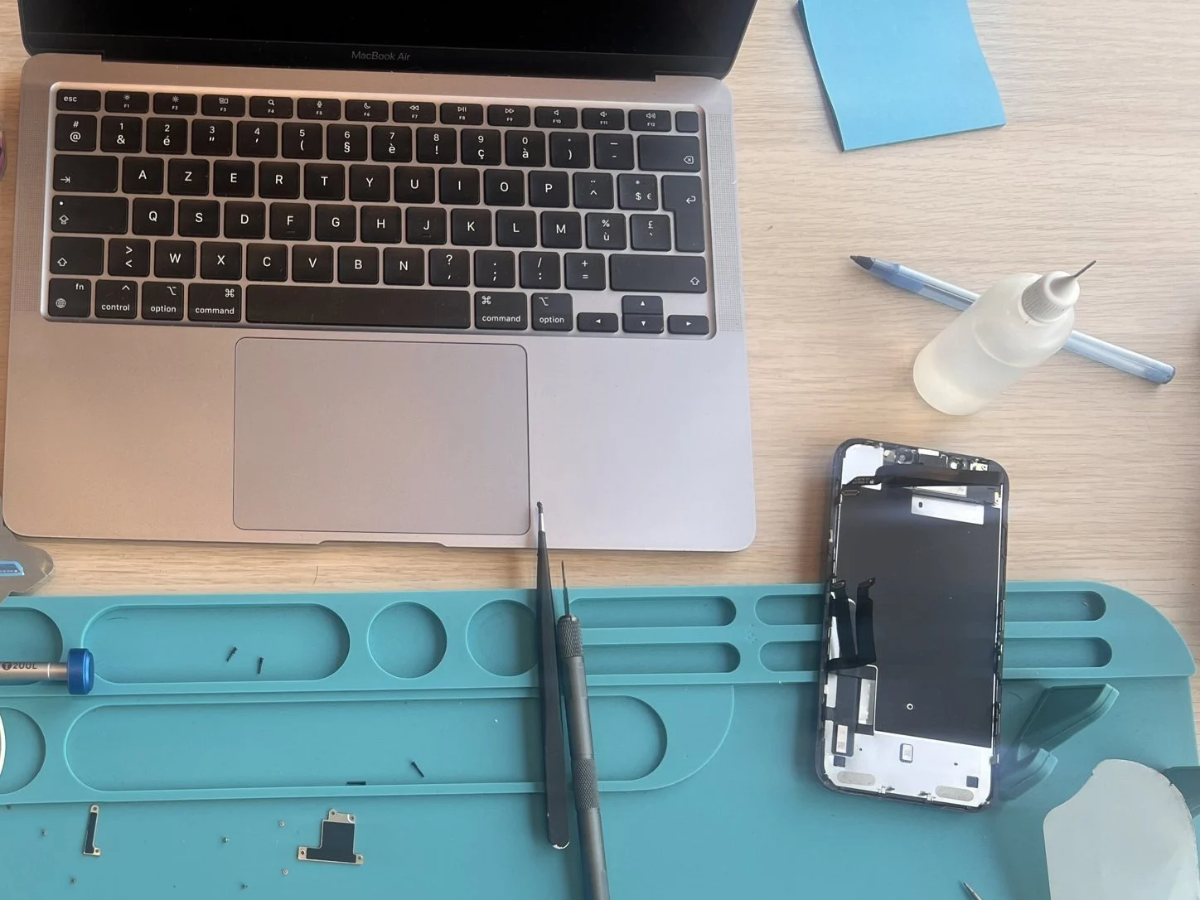 Dépannage informatique : MacBook et iPhone en cours de réparation sur le poste de travail de Repair Place à Chamalières